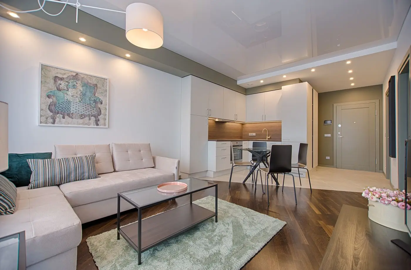 A compact living room with a fabric sofa, pale cabinet doors, and a dark timber floor