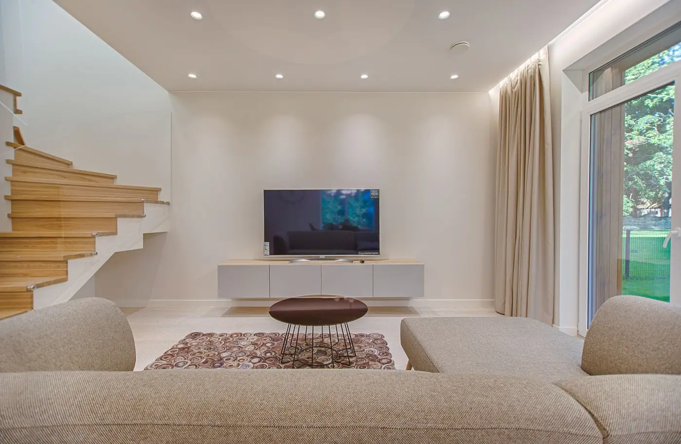 A fabric sofa facing a room with a tall window and curtains at the side